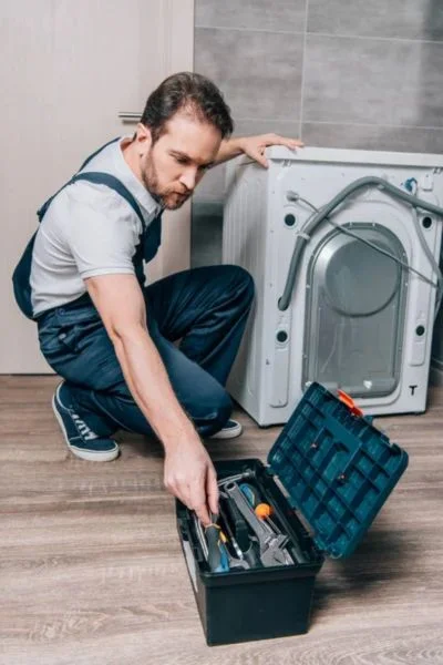Technik opravuje pračku v Brně s nářadím.