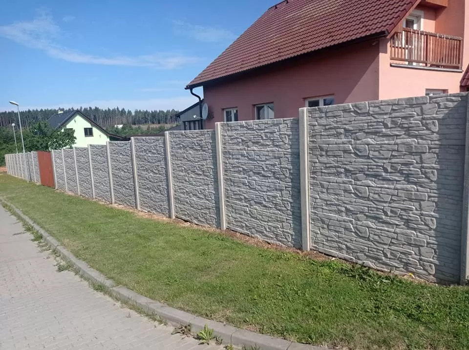 Konkrétní betonový plot s kamennou úpravou před domem.