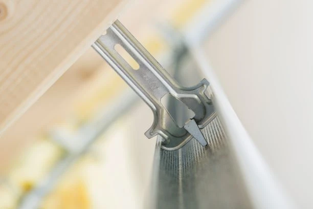 Detailní pohled na kovový závěs pro krokvu připevněný k dřevěnému nosníku.