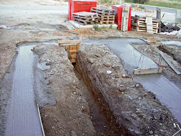 Základy budovy s čerstvě nalitým betonem v příkopu.
