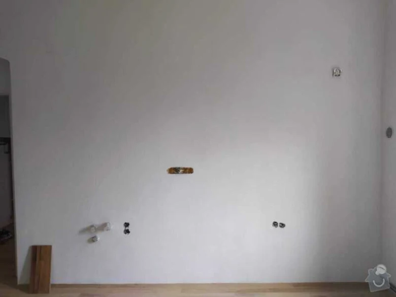 Nedokončené elektrické zásuvky na bílé stěně v interiéru.