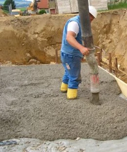 Pracovník míchá beton z pytle na staveništi.