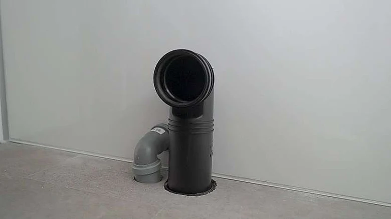 Černý odpadní potrubí s kolénkem v koupelně.