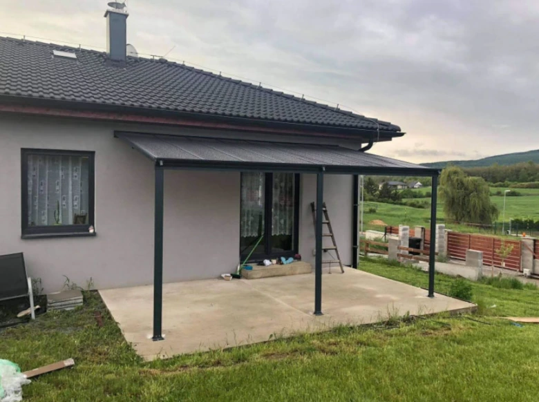 Montážní stavba pergoly s kovovými sloupky na zahradě.