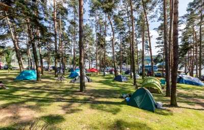 Kempování v lese s barevnými stanami u Vranovské přehradě.