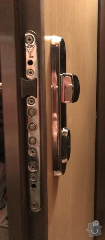 Detailní pohled na mechanismus zámku dveří s viditelnými šrouby.