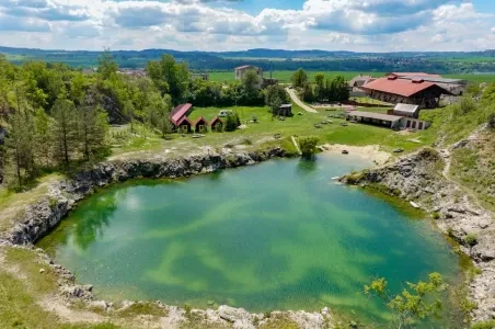 Venkovní bazén s jasnou vodou v přírodě mezi stromy.