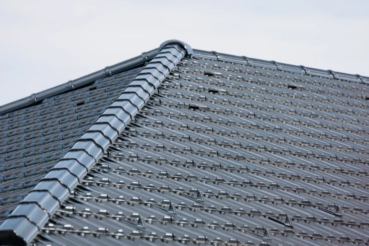 Detailní pohled na tmavé betonové střešní tašky s hřebenem.