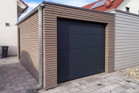 Moderní garáž s dřevěným obkladem a tmavými dveřmi.