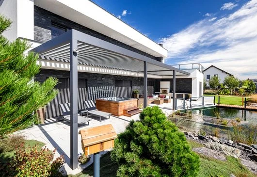 Moderní hliníková pergola s venkovním posezením u jezírka.