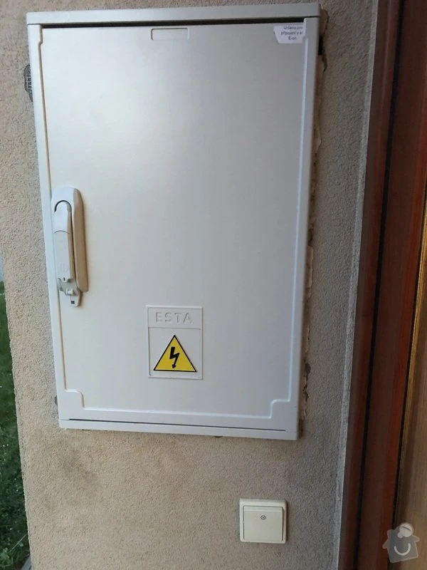 Bílá elektrická skříň na zdi s varovným štítkem pro elektro služby v Olomouci
