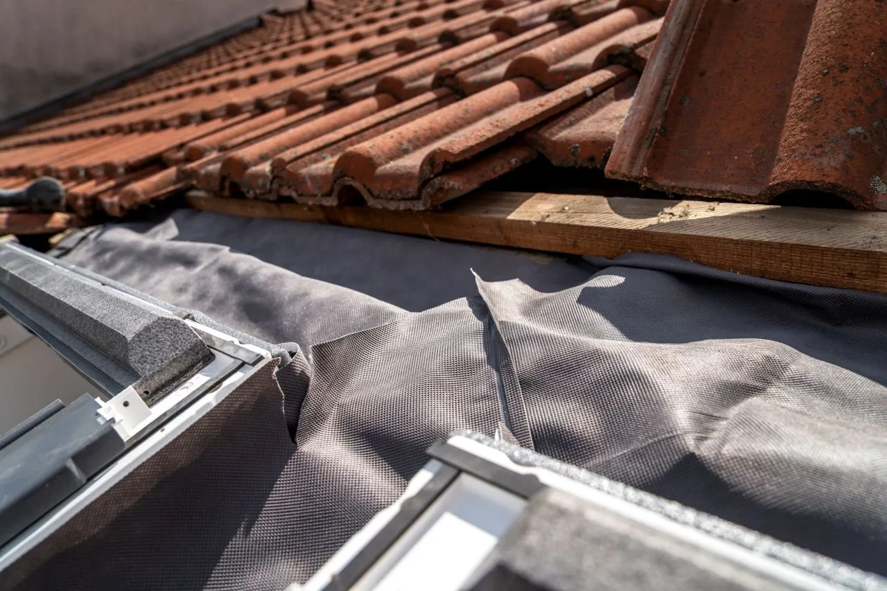 Detailní pohled na instalaci střešního okna s taškami a hydroizolací.
