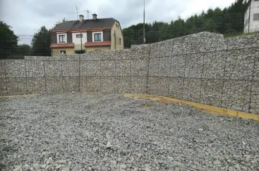 Hotová opěrná zeď z koryt s kamením před domem.