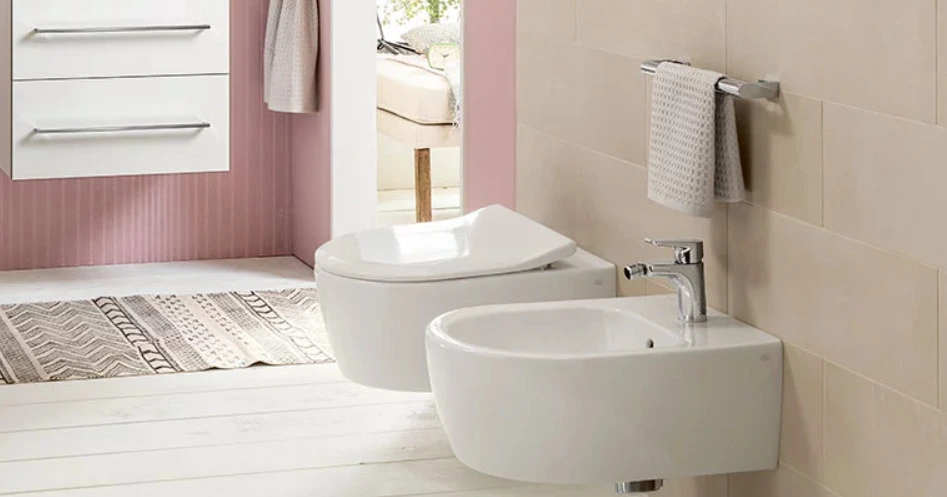Bílý nástěnný bidet vedle záchodu v moderní koupelně.
