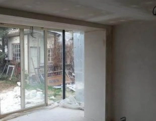 Nevyhotovaný interiér s nově nanesenou sádrovou stěrkou na zdi.