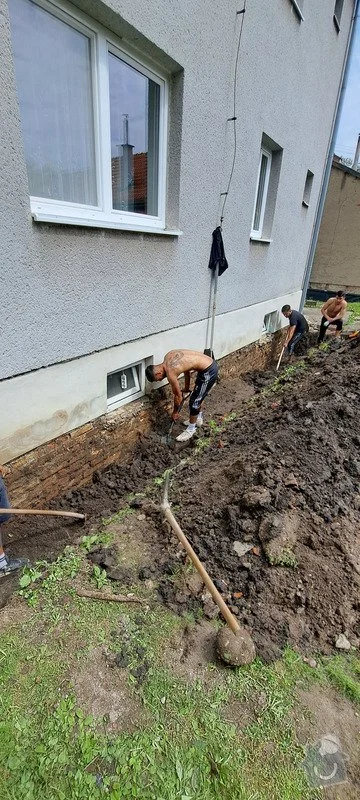 Muži bourají základovou zeď domu pro vložení překladu.