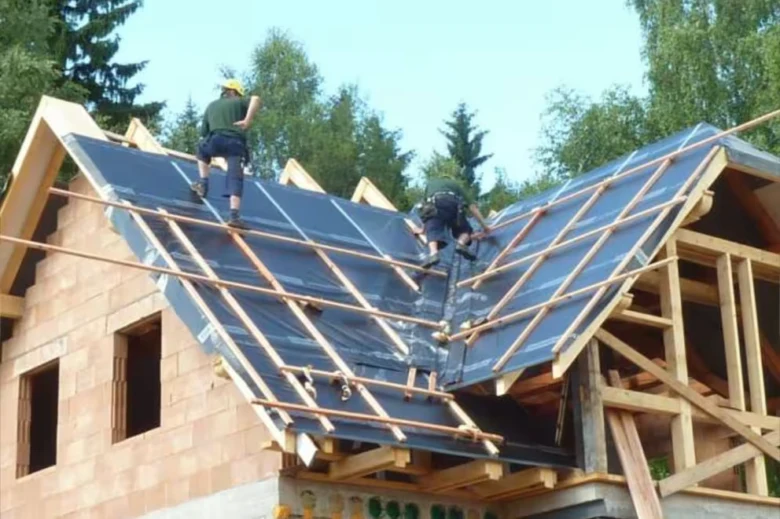 Montáž střešní fólie na dřevěnou konstrukci domu.