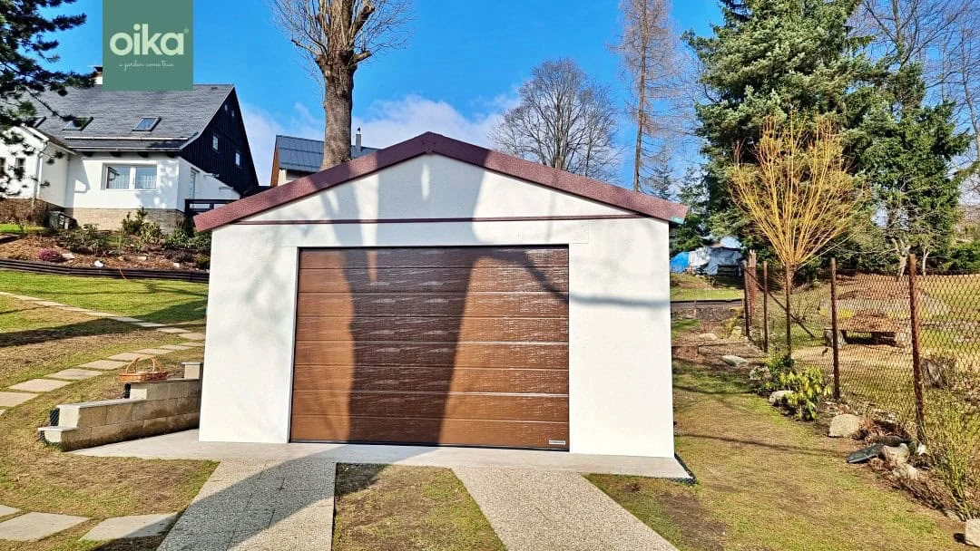 Moderní garáž s dřevěnými dveřmi na pozadí zelené trávy.