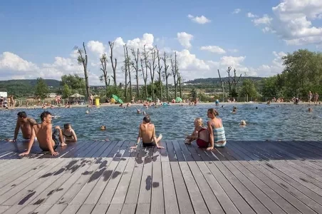 Lidé plavou v bazénu na venkově u Prahy.