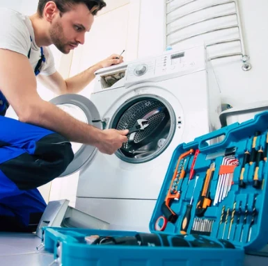 Technik opravuje pračku s otevřeným nářadím.