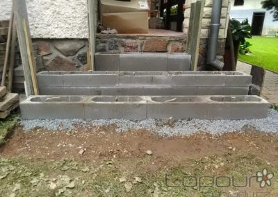 Nezhotovené betonové schody na zahradě vedoucí k domu.