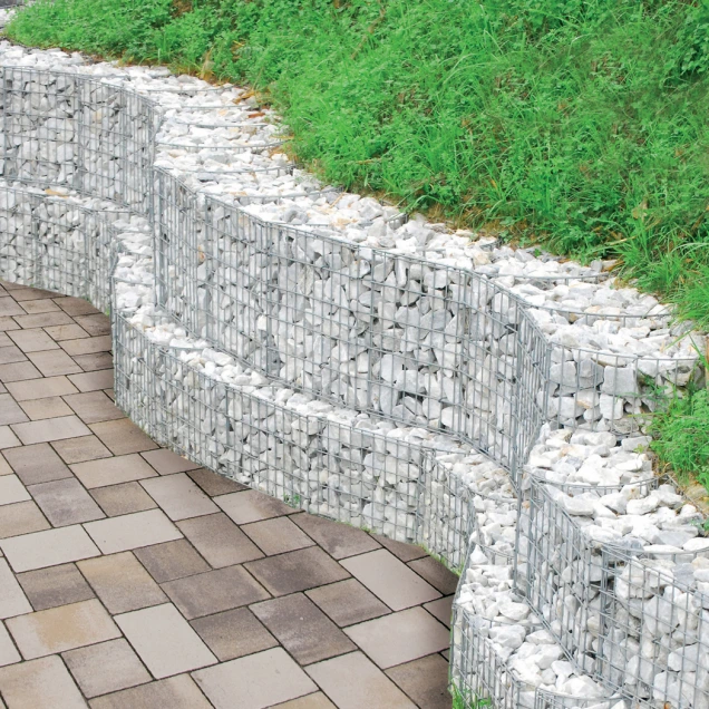 Křivá palisáda z košíků s kamenem na svahu zahrady.